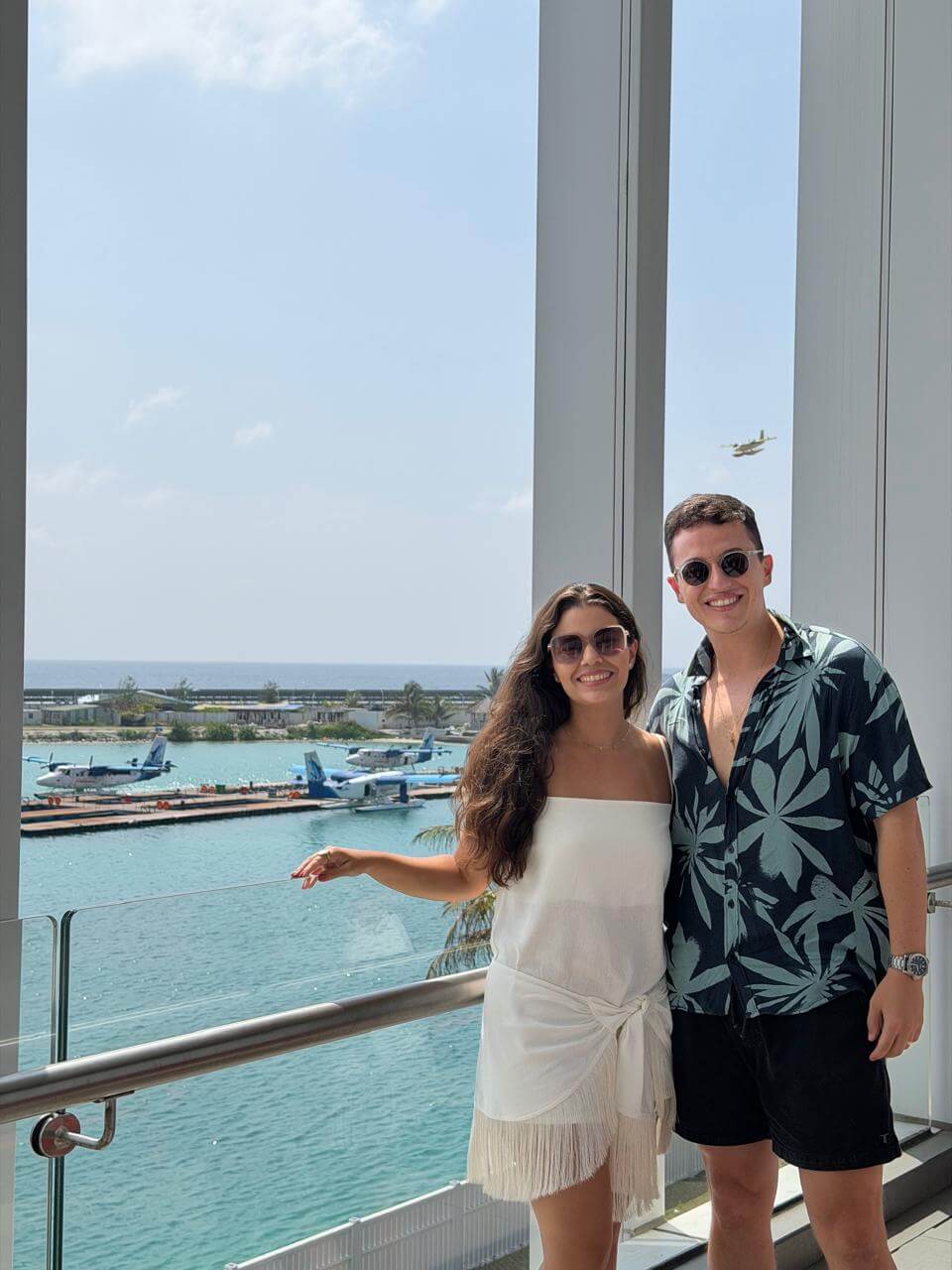 Casal na varanda do Lounge Infinity assistindo aos hidroaviões pousarem no terminal de seaplanes das Maldivas