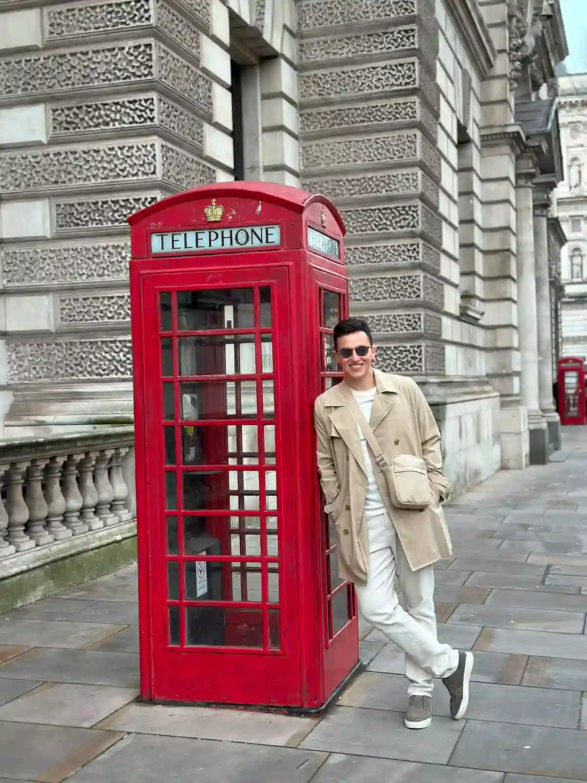 Homem ao lado de uma cabine telefônica vermelha tradicional de Londres