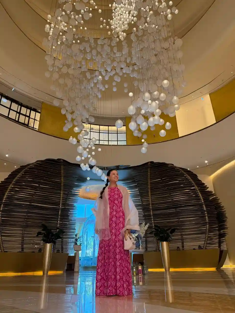 Mulher no hall de entrada do Fairmont Doha, com lustre icônico ao fundo