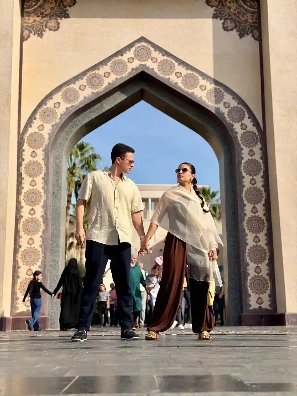 Casal caminhando sob arco de pedra no Katara Cultural Village em Doha