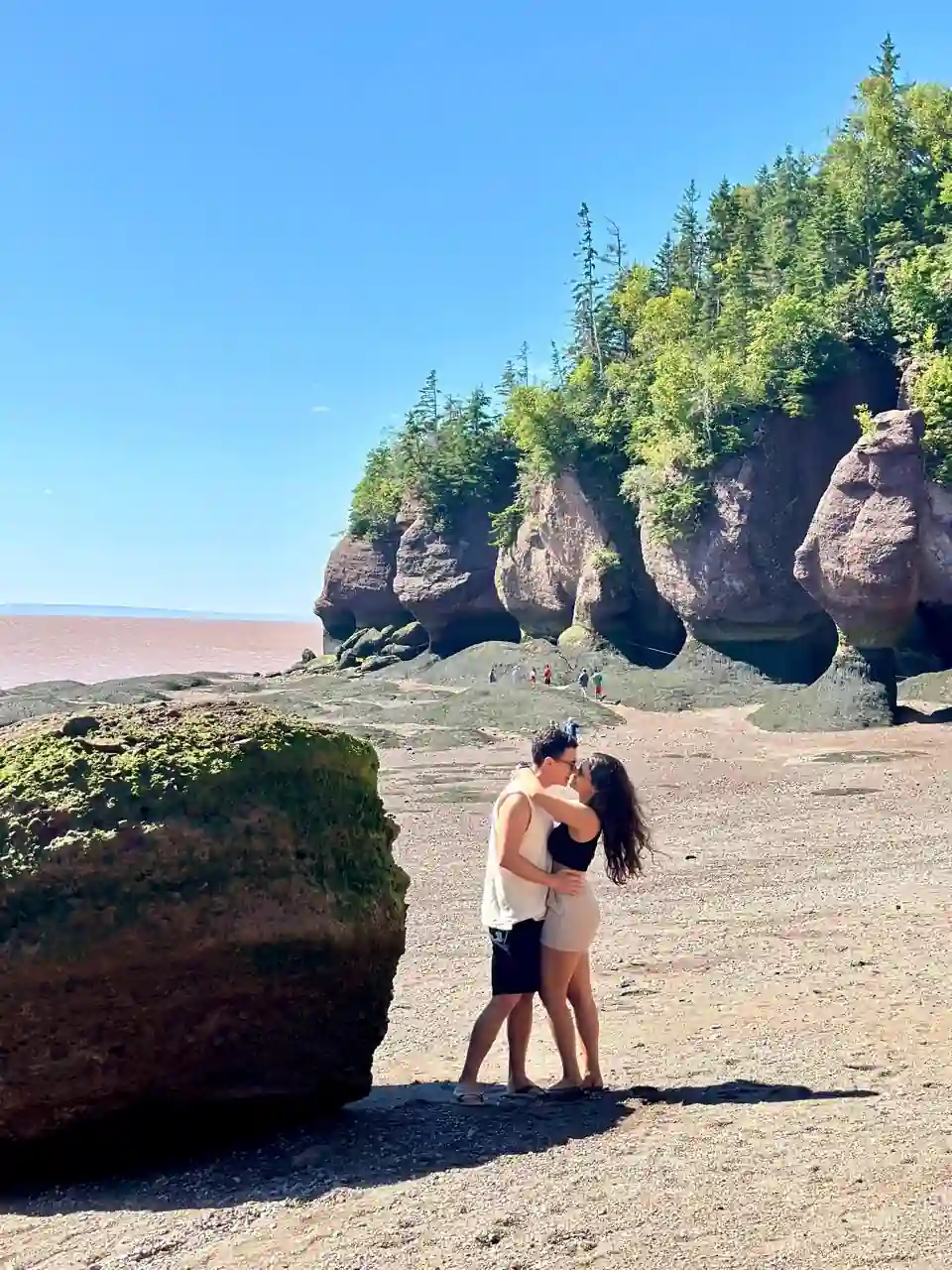 Casal se beijando no fundo do oceano descoberto pela maré baixa em Hopewell Rocks, Canadá