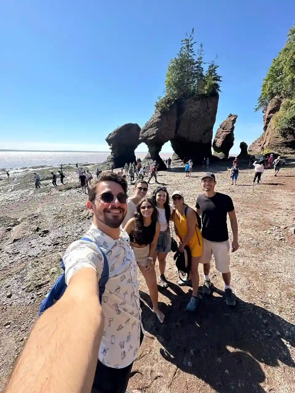 Grupo de amigos caminhando no fundo do oceano durante a maré baixa em Hopewell Rocks, New Brunswick