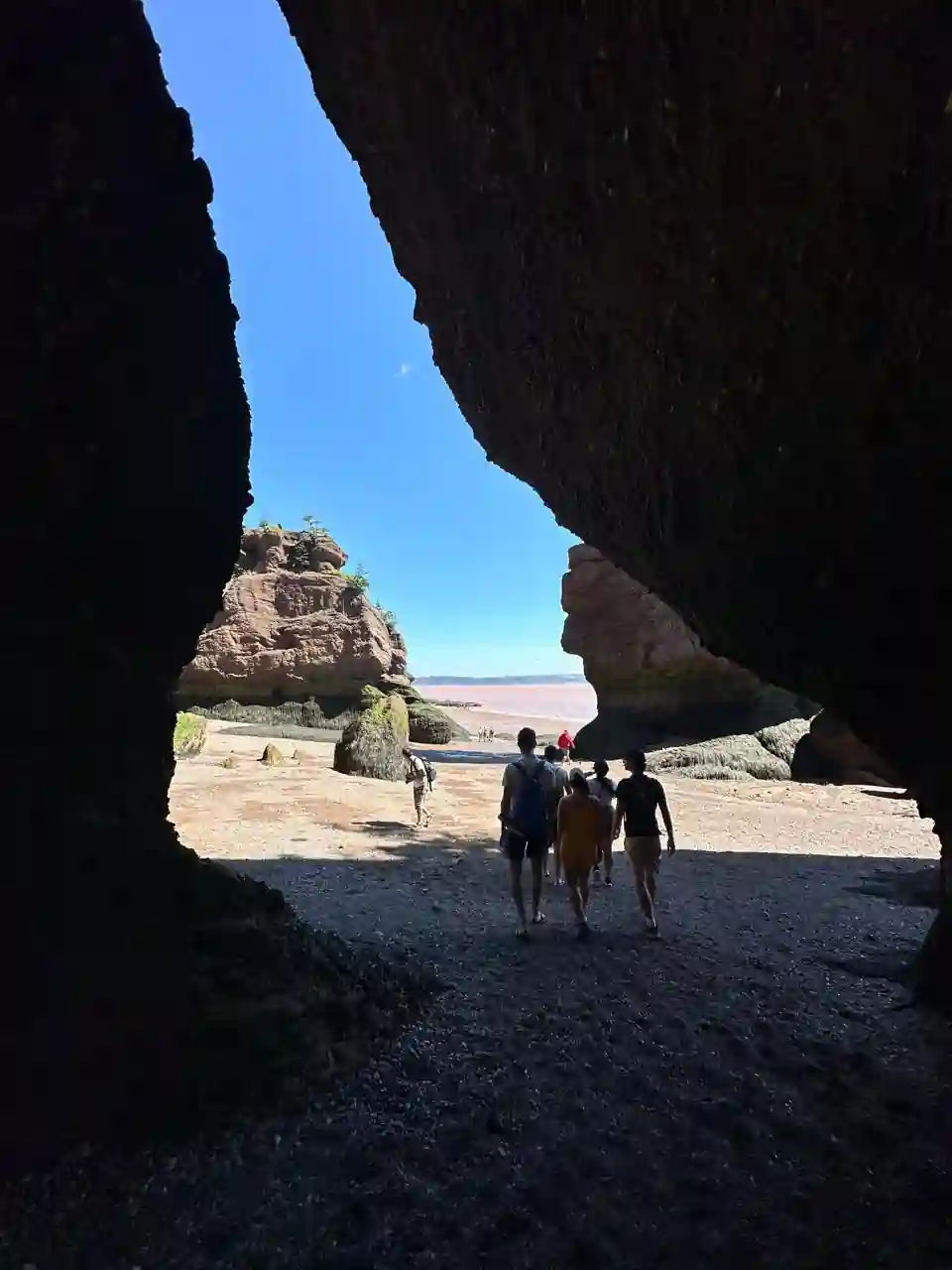 Grupo passando por gruta entre as rochas de Hopewell Rocks durante a maré baixa na Baía de Fundy