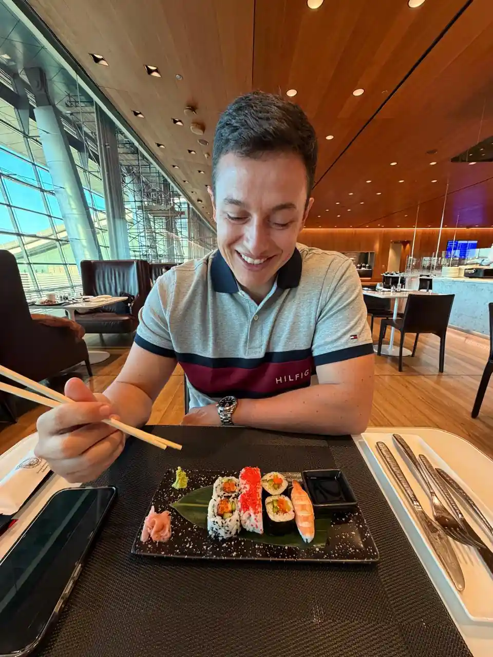 Homem comendo sushi no restaurante à la carte da Al Mourjan Business Lounge no aeroporto de Doha