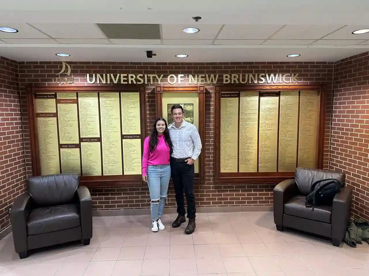 Casal em frente ao mural da University of New Brunswick (UNB) em Fredericton