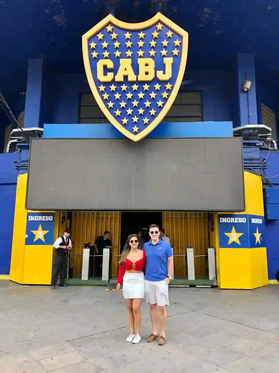 Casal na entrada do estádio La Bombonera, com o escudo do Boca Juniors, em Buenos Aires